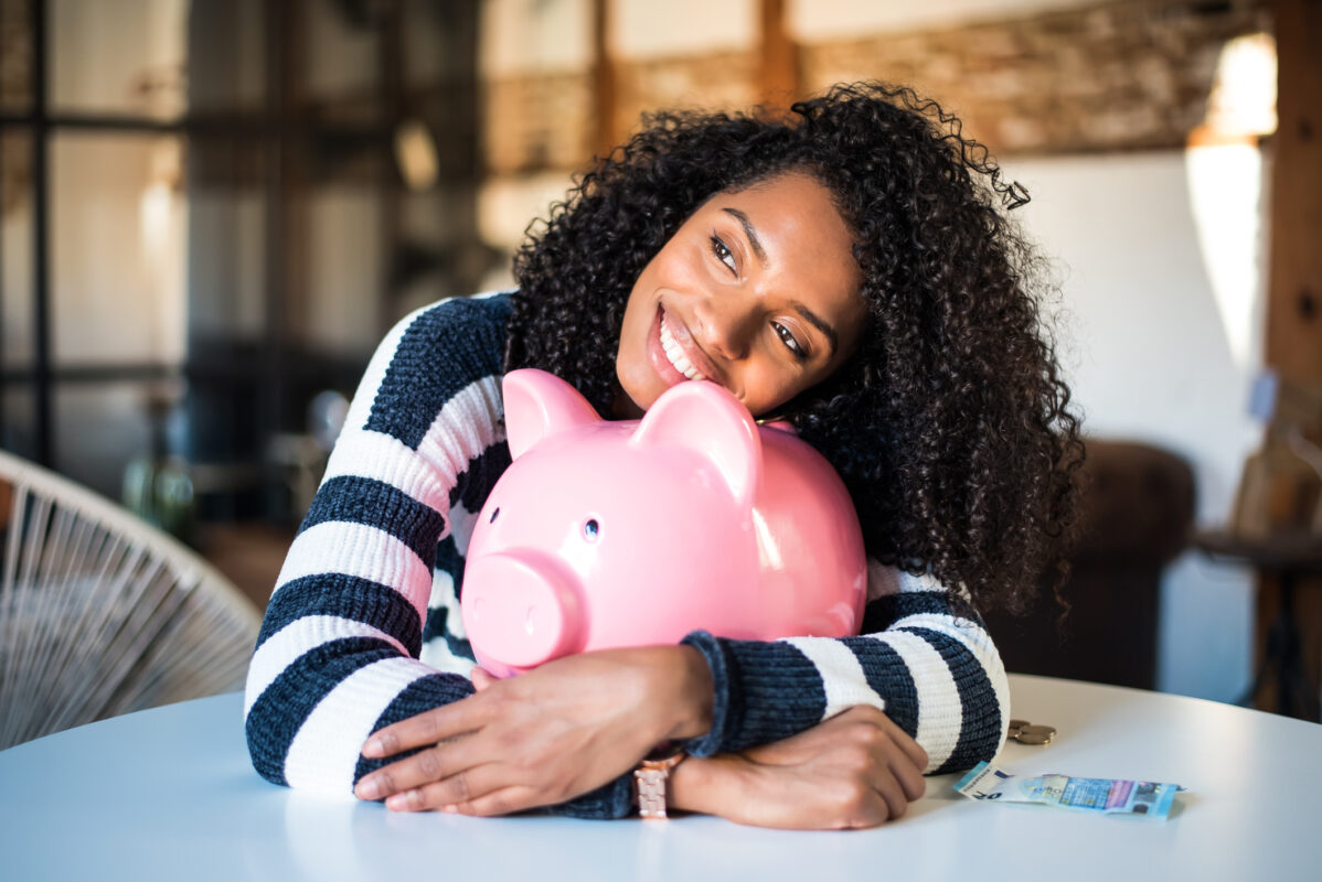 young black woman hugging her piggy bank saving for house deposit