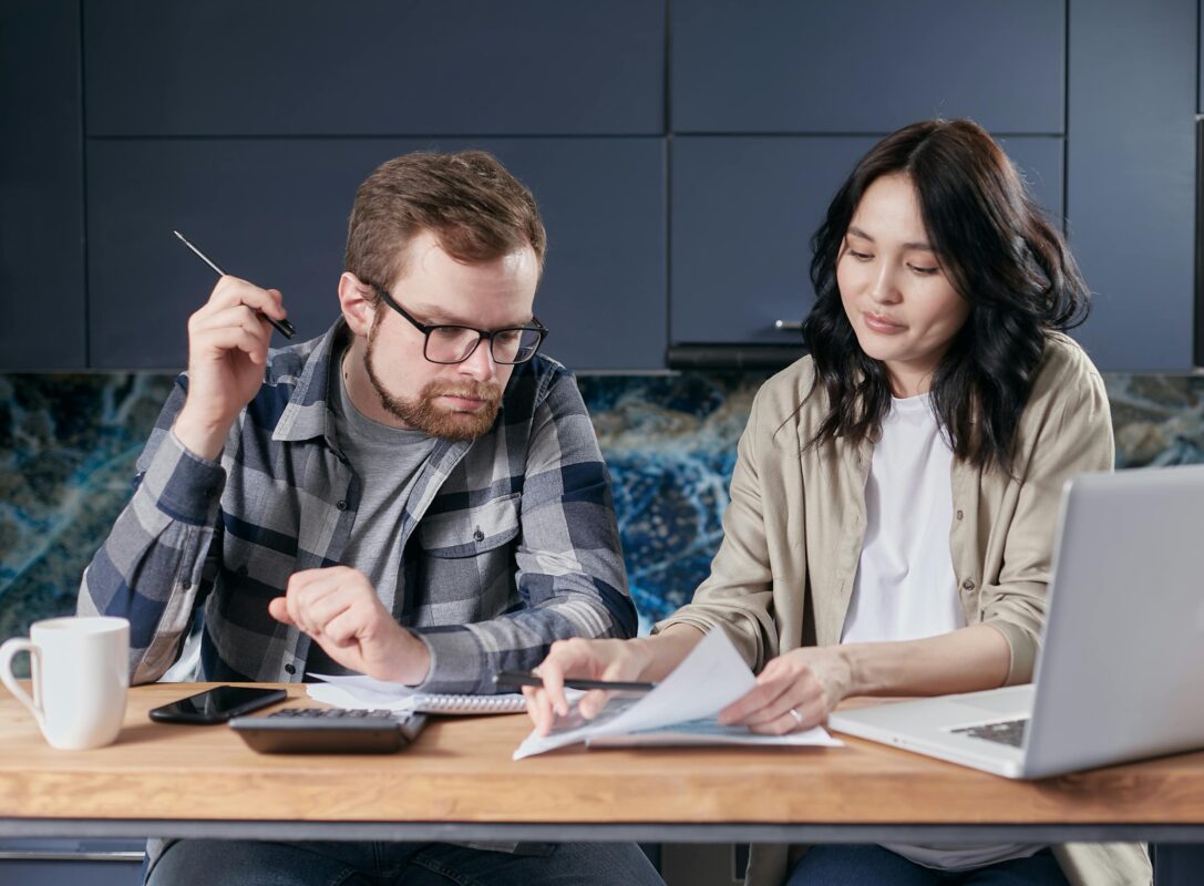 couple with paperwork, laptop and calculator working out the cost of moving