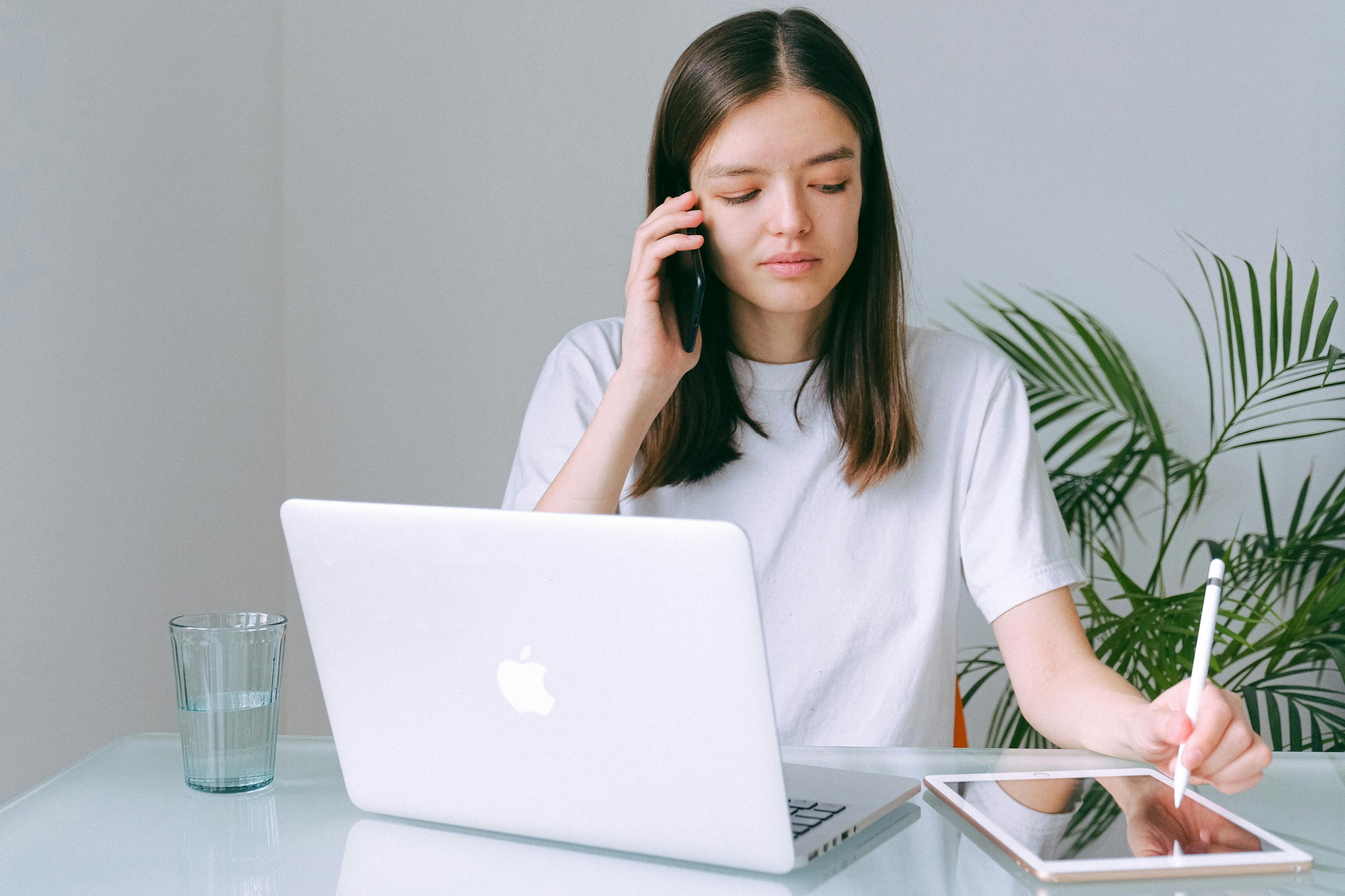 Young white lady on the phone at ha desk with a laptop