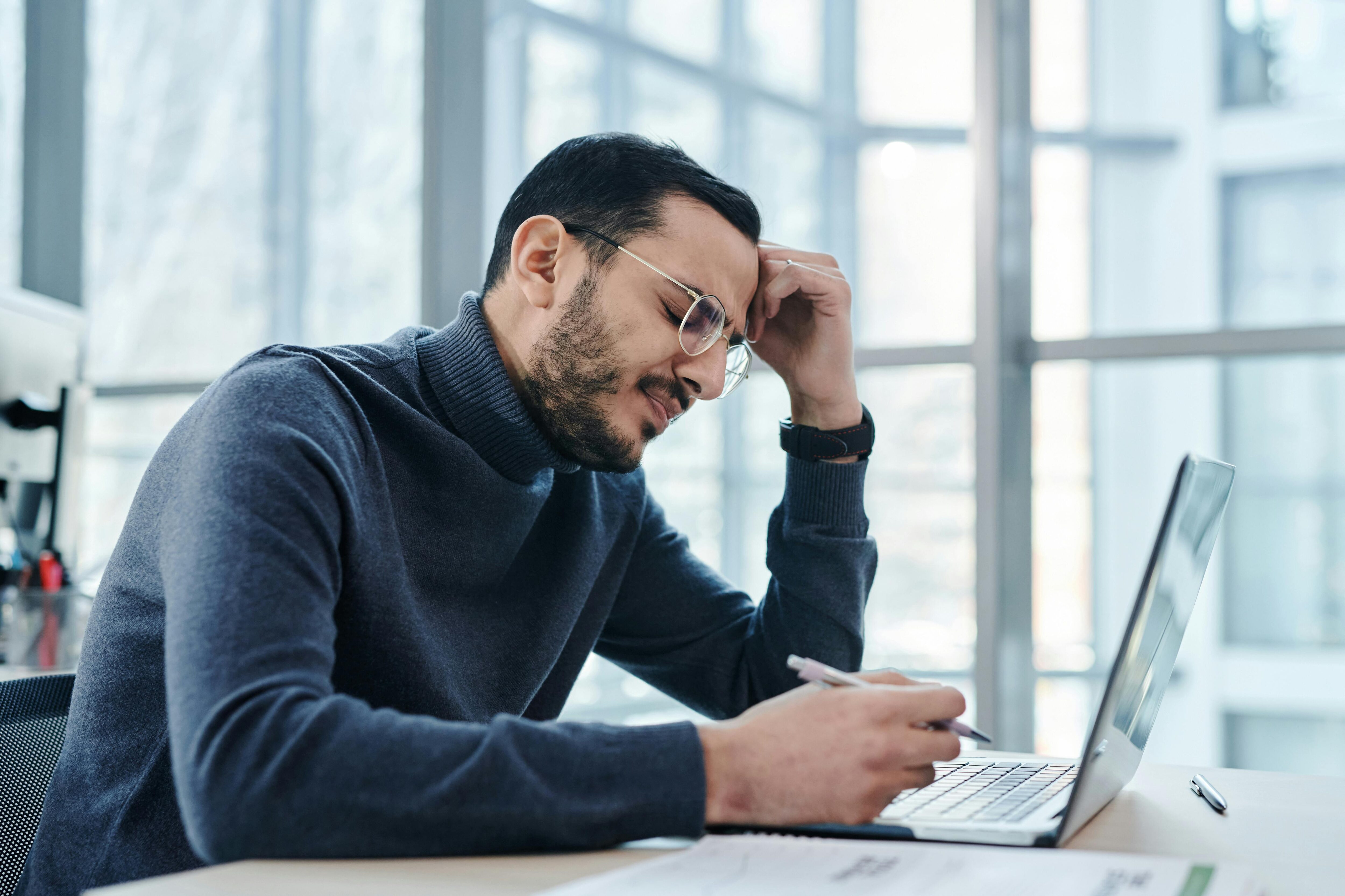 Middle-aged man with a beard, glasses and polo neck jumper working at a laptop