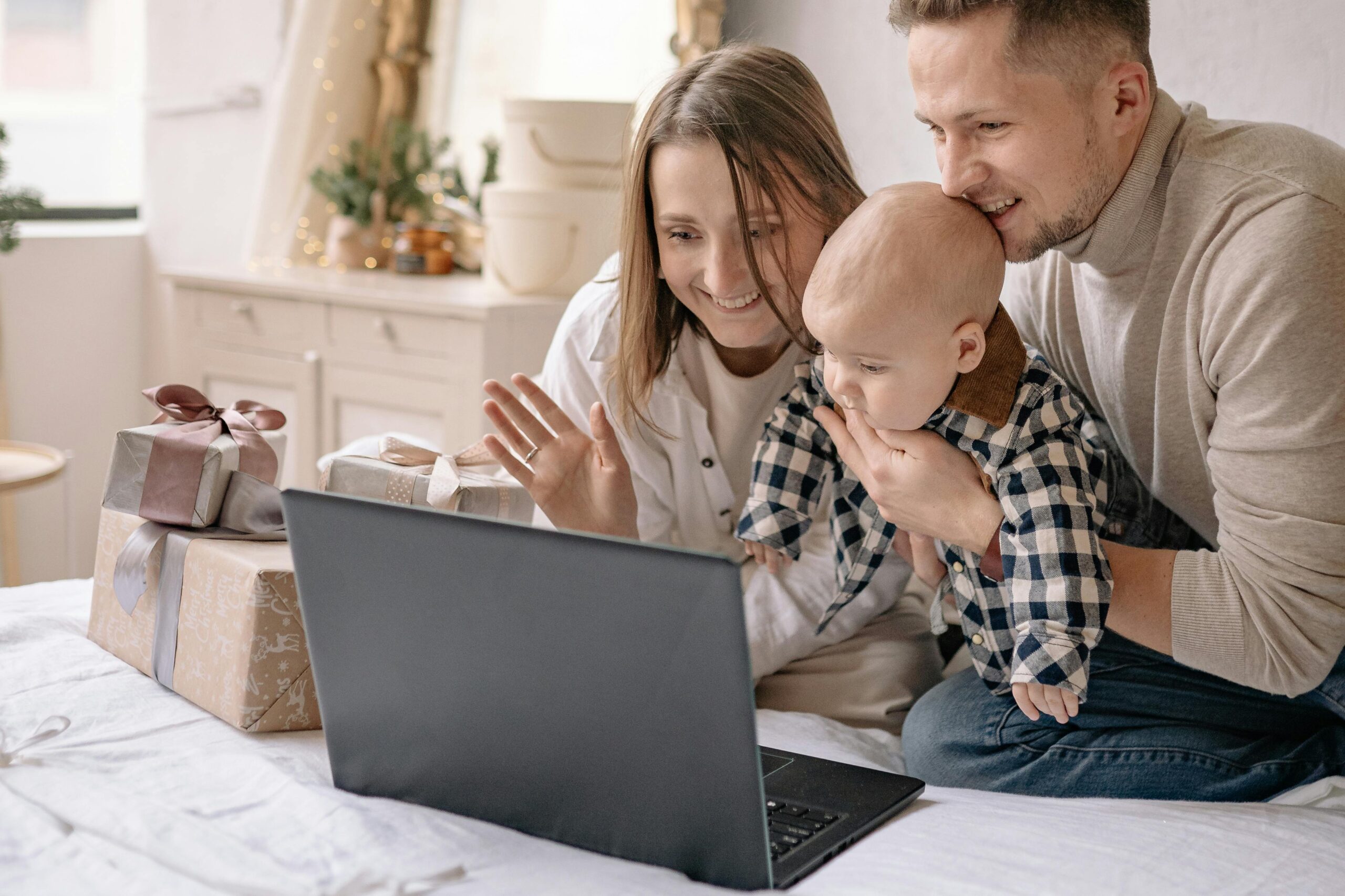 Happy male and female couple with their baby, happy at home looking at a laptop.